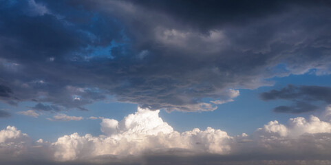 Naklejka na ściany i meble Dramatic sky with dark stormy clouds and white cumulus clouds near horizon