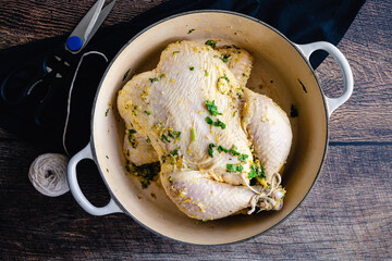 Cuban Mojo Chicken Ingredients on a Wood Background: Raw whole chicken, citrus fruit, cilantro, and...