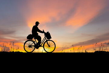 Fototapeta na wymiar Silhouette of Senior Asian man riding a bicycle at sunset in evening time
