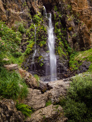Cascada de un río de montaña que cae entre rocas y vegetación.
