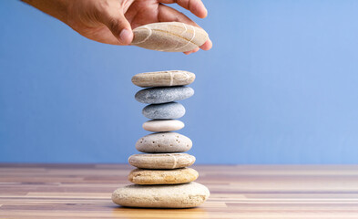 Hand stacking pebbles to make shape of hourglass as a symbol of time management. Concept of...
