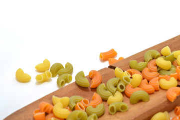 colored noodles on wooden board with a white background