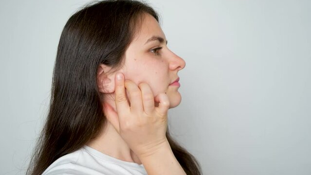A woman with temporomandibular joint dysfunction massages the masticatory muscles.