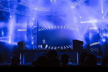 Dj playing techno music on the night concert in summer