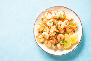 Shrimps with spices in craft plate at blue table. Top view with space for text.