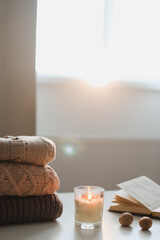 cozy comfortable hygge home atmosphere and still life with a cup, candle, book and sweaters