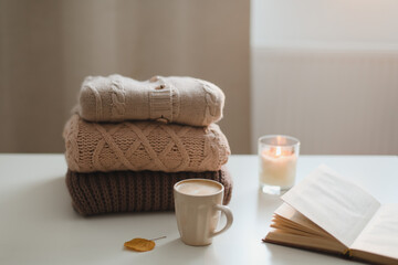 cozy comfortable hygge home atmosphere and still life with a cup, candle, book and sweaters