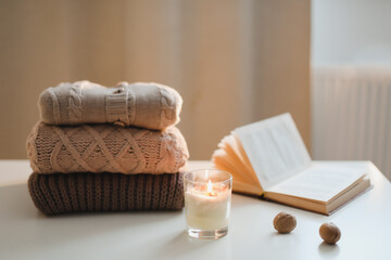 Fototapeta na wymiar cozy comfortable hygge home atmosphere and still life with a cup, candle, book and sweaters