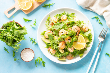 Shrimp salad with arugula and avocado at blue table. Top view with space for text.