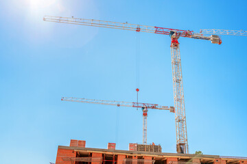 Construction cranes on a blue sky background