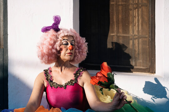 Eccentric female clown with flower during street performance