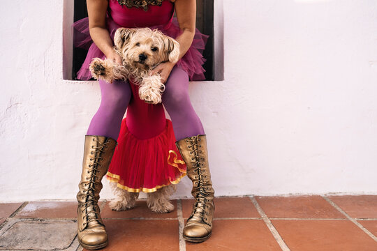 Anonymous female circus artist hugging dog on street