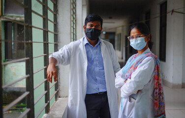 South asian young doctor in apron and face mask, medical student in hospital corridor 