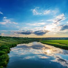 Amazing sunset in a blue cloudy sky over a river with green banks. Southern Ukraine landscape.