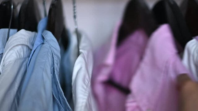 Woman choosing shirts in a wardrobe, close up