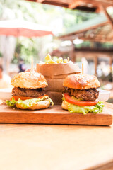 Four hamburgers on a wooden board and french fries served in a wooden paper basket