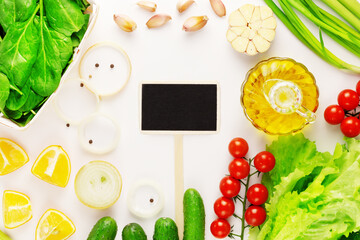 Healthy food. Organic, farm vegetables, olive oil and empty chalkboard on a white background. The concept of vegan diet and detox. Ingredients for vegetables salad. Flat lay