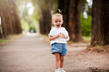 One young little child walking, strolling through a green field, rural forest area walk, school age girl wandering alone, copy space. Serene outdoor scene, children healthy active lifestyle concept
