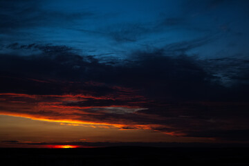 Fototapeta premium Dramatic landscape of sunset with dark colourful clouds. Natural background.