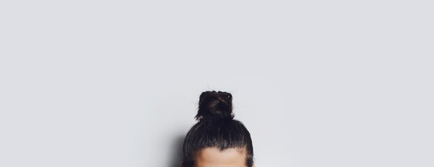 Close-up of brunette hair bun on grey background. Panoramic banner view.