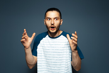 Fototapeta premium Studio portrait of shocked guy in shirt, on blue background.