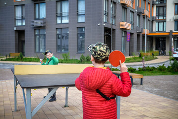 Two happy boys, teenager twin brothers, enjoying vacation playing ping pong outdoors. Active...