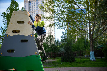 Teenager boy climbing at kid playground outdoor. The climber tra