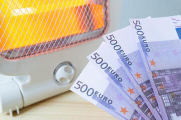 Euro bills against the background of the electric heater on. The concept of rising electricity prices, energy savings.