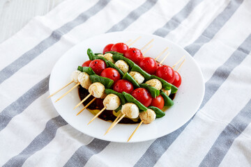 Homemade caprese skewer appetizer on a plate, side view.