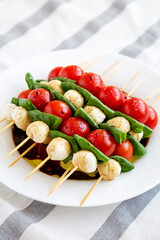 Homemade caprese skewer appetizer on a plate, side view.