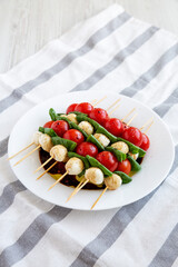 Homemade caprese skewer appetizer on a plate, side view.