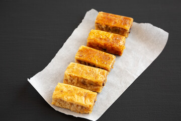 Homemade Baklavas with Honey, Chocolate and Almond on a black background, side view.