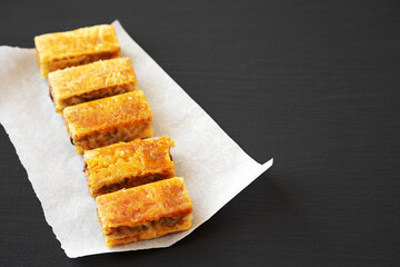 Homemade Baklavas with Honey, Chocolate and Almond on a black background, side view. Space for text.