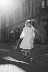 A young woman in a white dress walks through the streets of the city. People, fashion,  lifestyle, travel and vacations concept