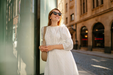 A young woman in a white dress walks through the streets of the city. People, fashion,  lifestyle, travel and vacations concept