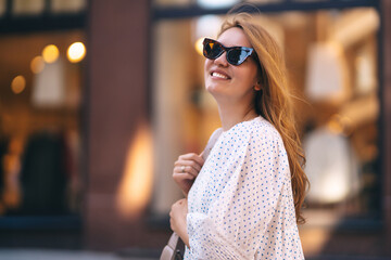 A young woman in a white dress walks through the streets of the city. People, fashion,  lifestyle, travel and vacations concept