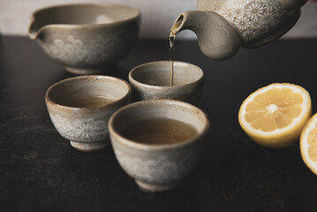 Pouring Korean tea into teacups with lemon and loose leaf tea
