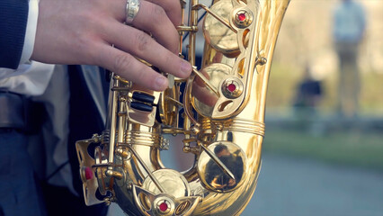 Young man with saxophone outside near the old painted wall. Young expressive musician playing the...