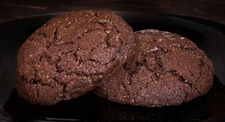 Fototapeta premium Wheat cookies dark with cracks on a black plate