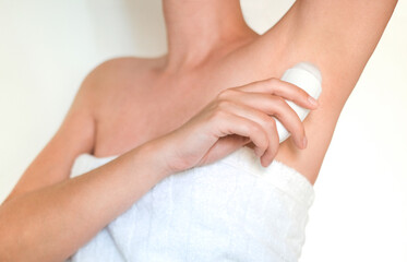 woman in towel after shower uses roll-on deodorant close-up