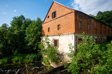 Fototapeta na wymiar Old abandoned red brick watermill. Architectural monument of the 19th century.