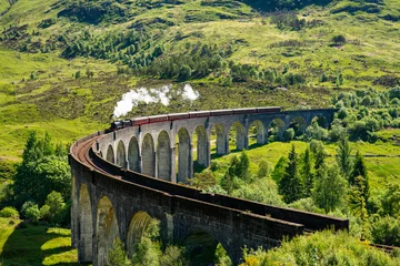 Fotobehang Glenfinnanviaduct Glenfinnan Spoorwegviaduct in Schotland met de stoomtrein die overgaat