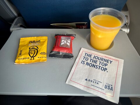 MISSOULA, MT, MAY 2021: airline snacks and orange juice served on a Delta Airlines flight, on pull down seat table