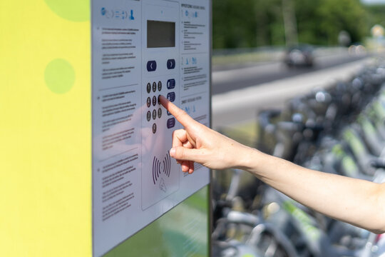 Woman unlock rented bike, press button on parking station