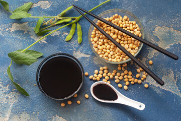 Organic, domestic soy beans and soy sauce in a glass bowl with leaves and green beans. Top view, blue background, with chopsticks. Healthy, vegan food.