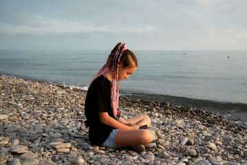 The girl sits and communicates online. Communication. Generation Z. Recreation. Sea.