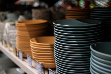 Variety of plates displayed on shelves at a department household goods store. Kitchen utensils and dishware for sale. Home decor and comfort concept