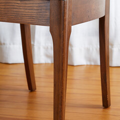 Detail view of the leg of a Mid Century Modern Broyhill Brasilia Dining Arm Chair in front of white drapes on a wood floor