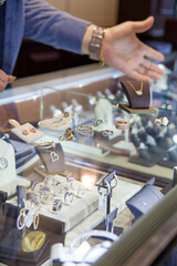 Man's hand displaying jewellery at a counter.