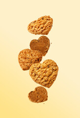 heart-shaped oatmeal cookies flying on a yellow background, selective focus